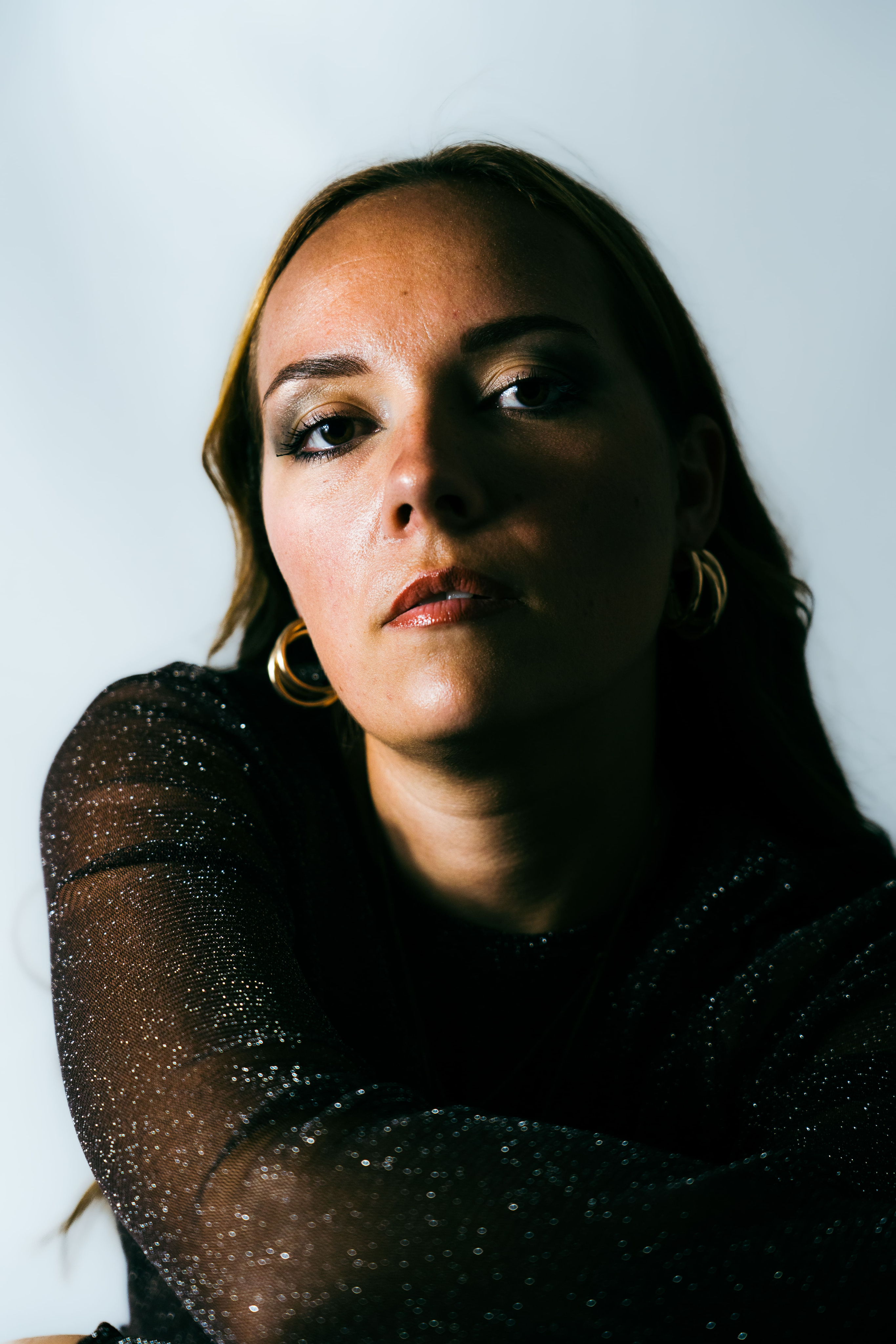 photo portrait de femme en studio fond blanc de près visage éclairé de moitié l'autre moitié dans l'ombre peau blanche cheveux longs chatains blonds photographge de mode chambéry grenoble